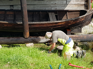 Bosse tjärar vaggan till museibåt i sjöboden.